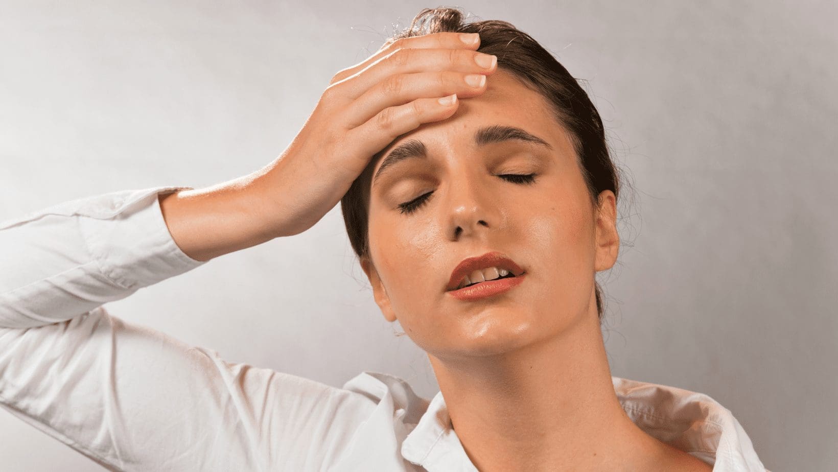 woman with hand on forehead and eyes closed