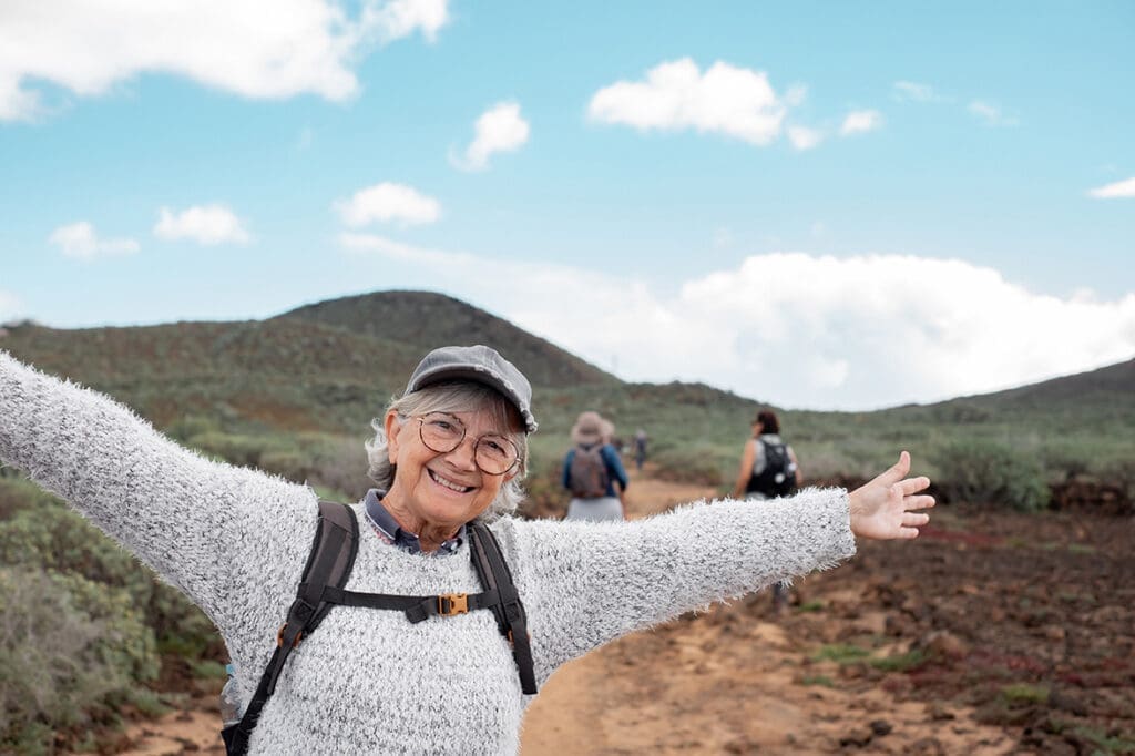 Elderly woman smiling on a hike pain free thanks to professional chiropractic care.