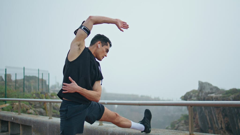 A male runner stretches after a run with ease thanks to a increased range of motion from massage therapy.